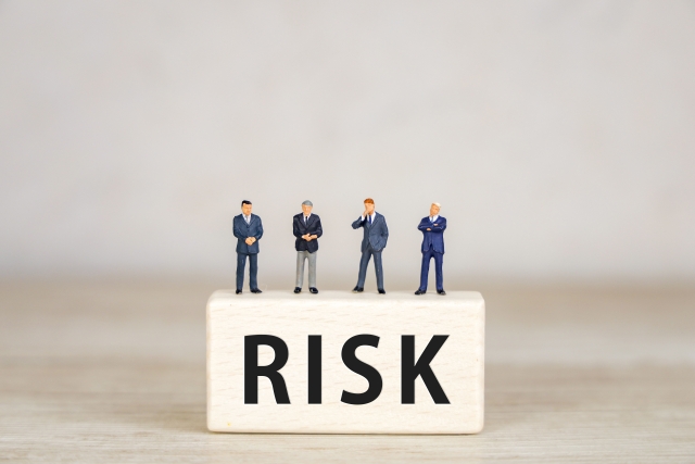 リスクと書かれたブロックに乗るビジネスマン