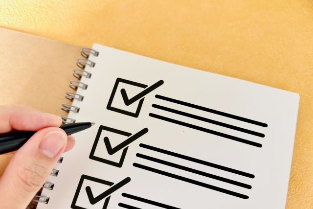 チェックシートとペンを持つ手元