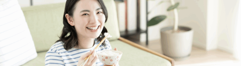 リビングでご飯を笑顔で食べる若い女性