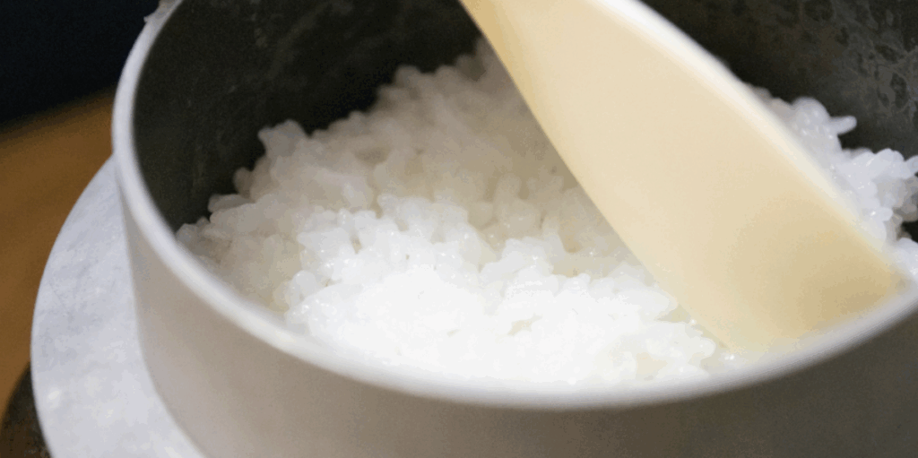 炊きたての白ご飯をしゃもじでほぐす釜内部のクローズアップ