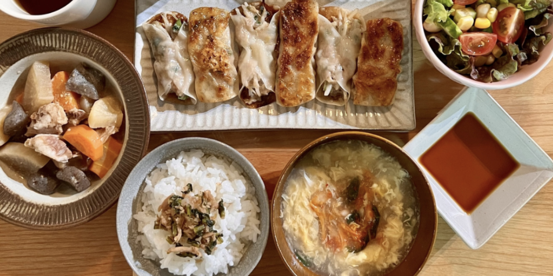 餃子・根菜の煮物・キムチスープ・サラダなど品数豊富な家庭料理の食卓上ビュー