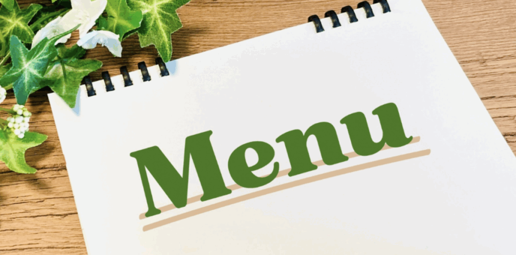 アイビーの葉と一緒に置かれたスケッチブックの表紙に緑色で書かれた『Menu』の文字